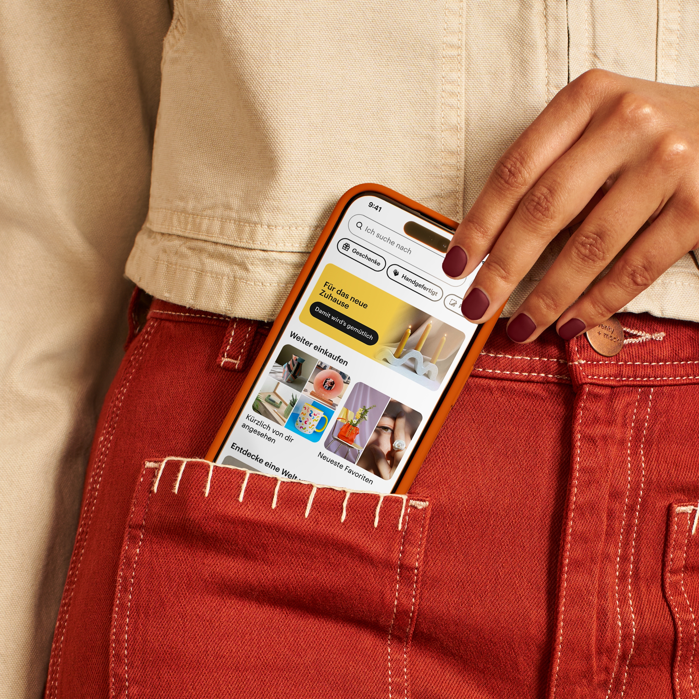 Hand einer Person, die ein Telefon aus der Hosentasche zieht, auf dem die Etsy-Website abgebildet ist.